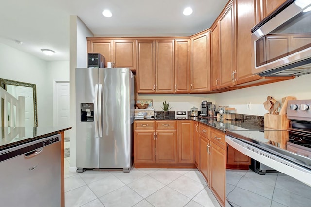 kitchen with dark stone countertops, light tile patterned floors, and appliances with stainless steel finishes