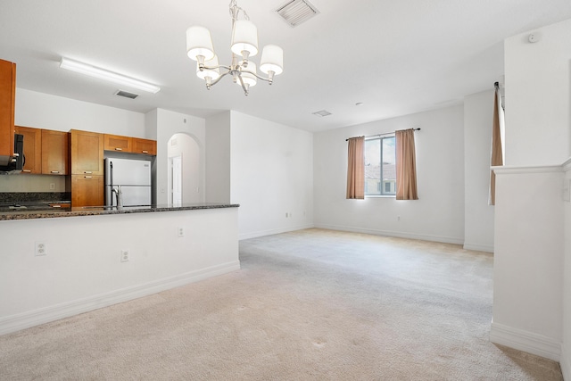 unfurnished living room with light carpet, sink, and a chandelier