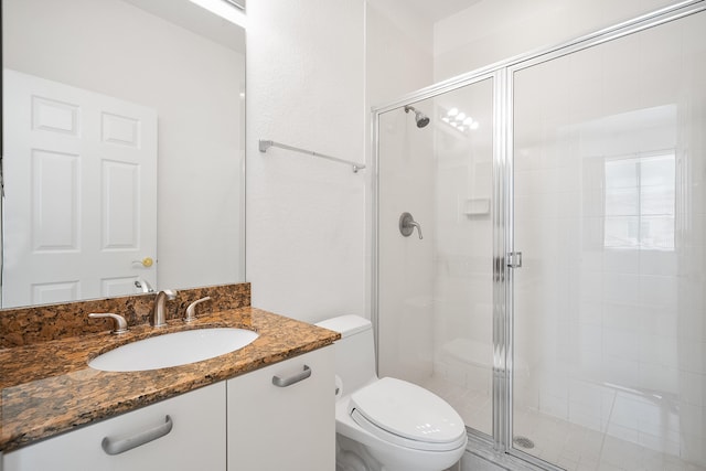 bathroom featuring a shower with door, vanity, and toilet