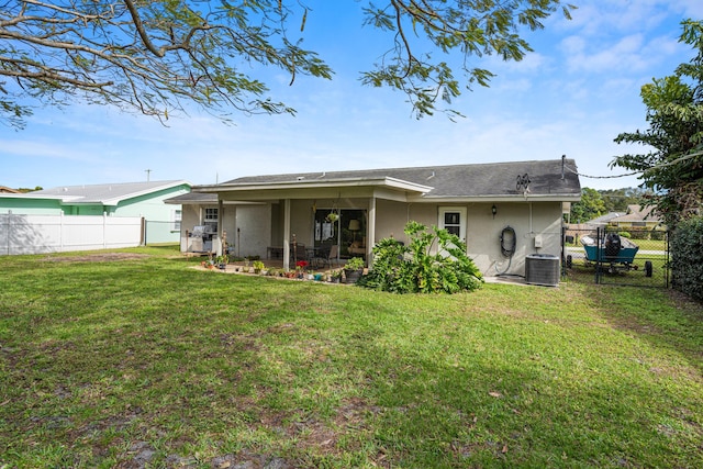 rear view of property featuring a lawn and central air condition unit