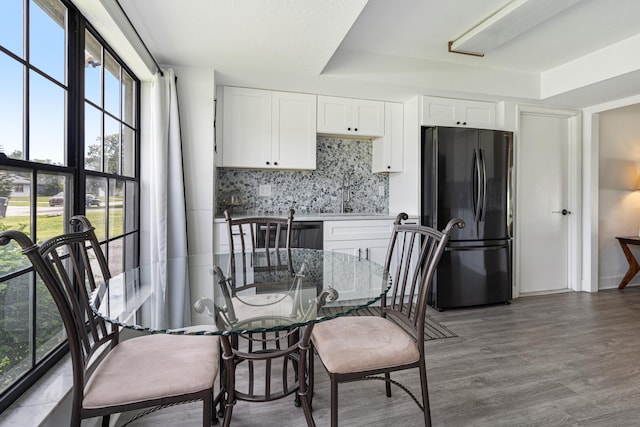 kitchen with sink, white cabinetry, wood-type flooring, black appliances, and decorative backsplash