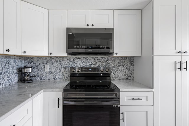 kitchen with black electric range oven, backsplash, light stone countertops, and white cabinets