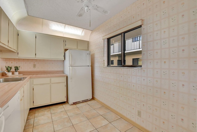 kitchen featuring light tile patterned flooring, sink, a textured ceiling, ceiling fan, and white appliances