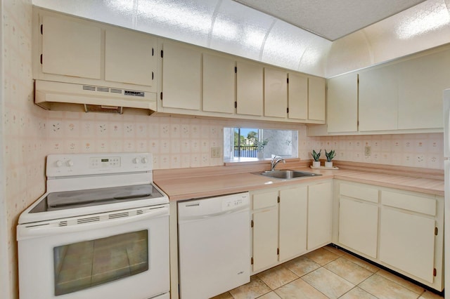 kitchen with cream cabinetry, sink, white appliances, and light tile patterned floors