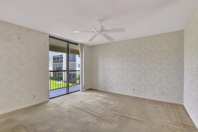 carpeted spare room featuring floor to ceiling windows, ceiling fan, and a textured ceiling