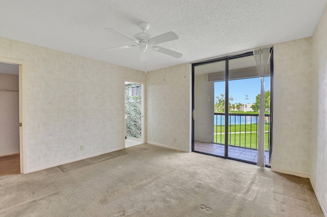 carpeted spare room with a water view, ceiling fan, and a textured ceiling