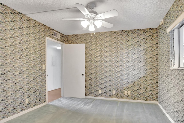 carpeted empty room featuring ceiling fan and a textured ceiling