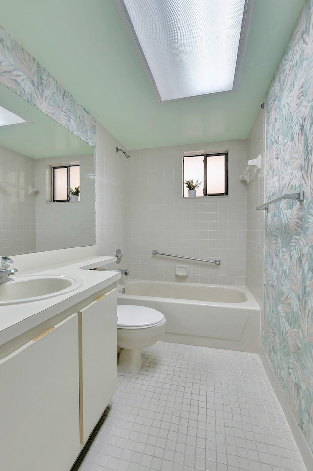 full bathroom featuring tile patterned flooring, tiled shower / bath, vanity, and toilet