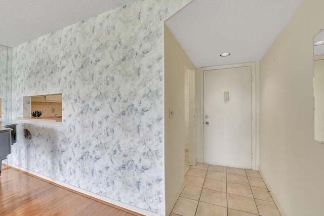 corridor with light tile patterned flooring and a textured ceiling