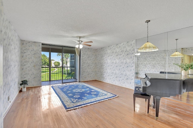 misc room with hardwood / wood-style flooring, ceiling fan, and a textured ceiling