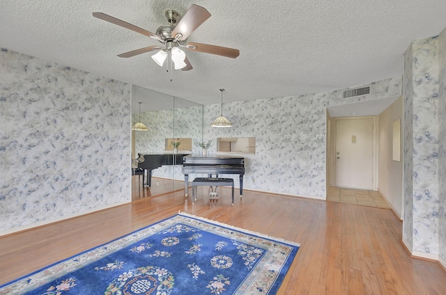 interior space featuring ceiling fan, hardwood / wood-style floors, and a textured ceiling