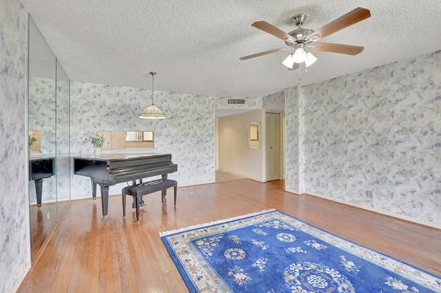 miscellaneous room with ceiling fan, hardwood / wood-style floors, and a textured ceiling