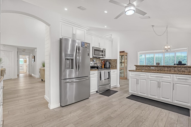 kitchen with appliances with stainless steel finishes, tasteful backsplash, white cabinetry, dark stone countertops, and light wood-type flooring