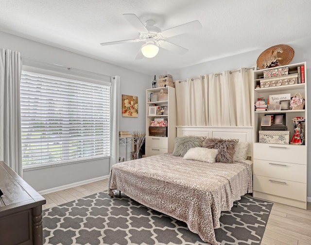 bedroom with ceiling fan, light hardwood / wood-style floors, and multiple windows