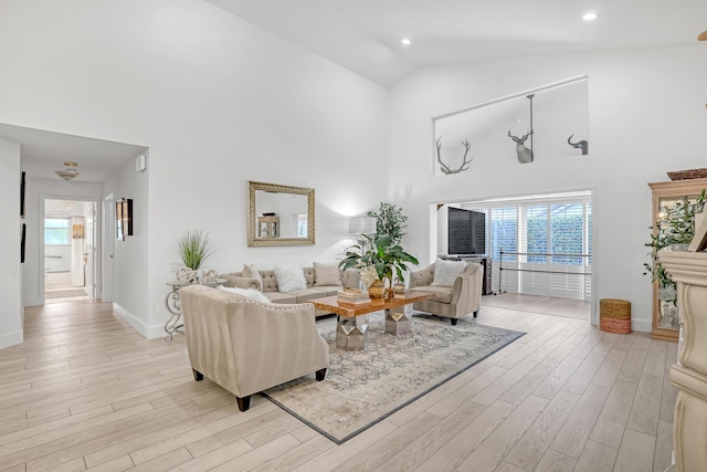 living room with plenty of natural light, high vaulted ceiling, and light hardwood / wood-style flooring