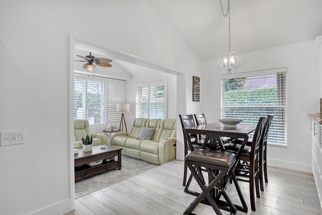 dining space featuring high vaulted ceiling, ceiling fan with notable chandelier, and light hardwood / wood-style floors