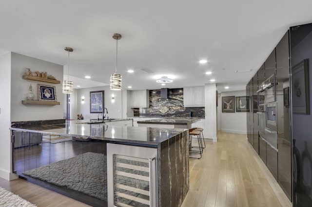 kitchen with white cabinetry, dark stone countertops, pendant lighting, beverage cooler, and backsplash