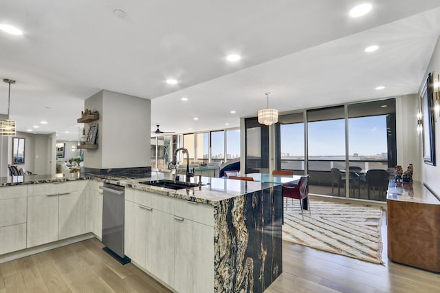 kitchen featuring sink, decorative light fixtures, light hardwood / wood-style floors, and stone countertops