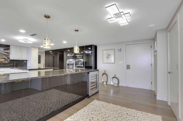 kitchen with wine cooler, tasteful backsplash, decorative light fixtures, dark stone countertops, and light hardwood / wood-style floors