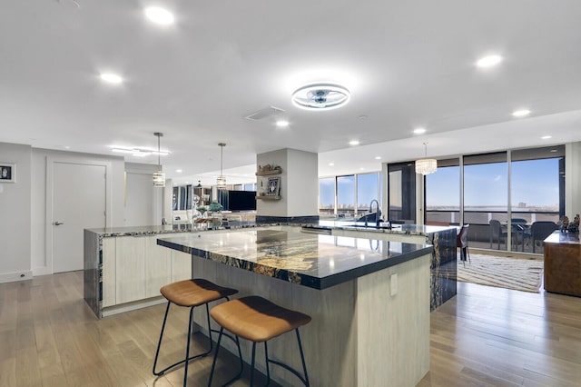 kitchen with hanging light fixtures, a spacious island, and dark stone counters