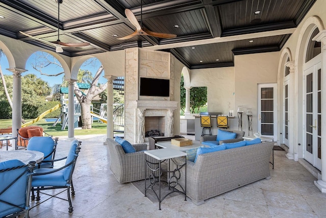 view of patio / terrace with an outdoor living space with a fireplace, a playground, and ceiling fan