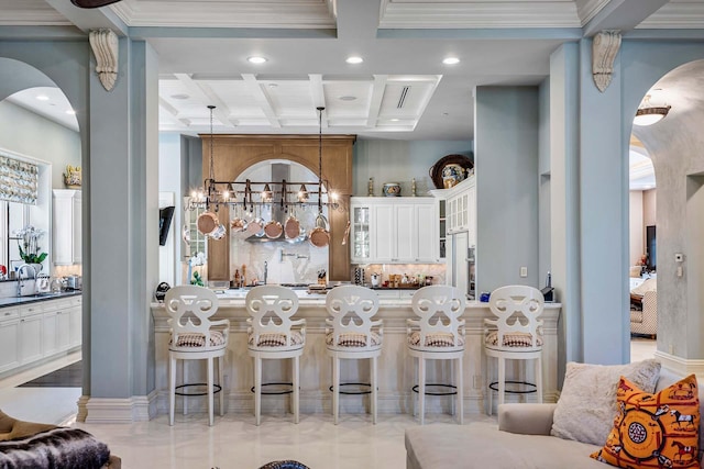 kitchen with pendant lighting, white cabinetry, a breakfast bar area, a high ceiling, and coffered ceiling