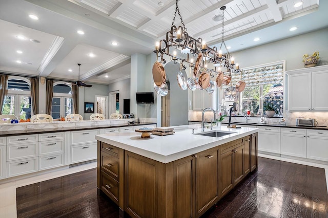 kitchen with sink, pendant lighting, an island with sink, beamed ceiling, and backsplash