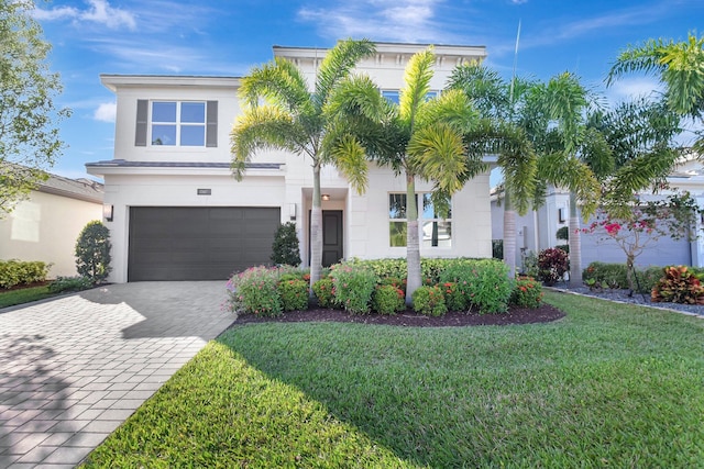 view of front facade with an attached garage, a front lawn, decorative driveway, and stucco siding