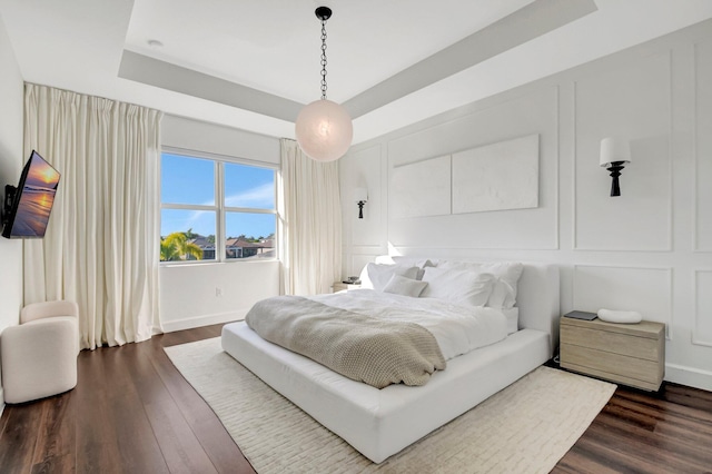 bedroom with dark hardwood / wood-style flooring and a tray ceiling