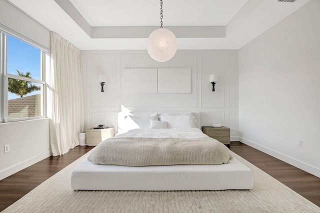 bedroom with hardwood / wood-style floors and a raised ceiling