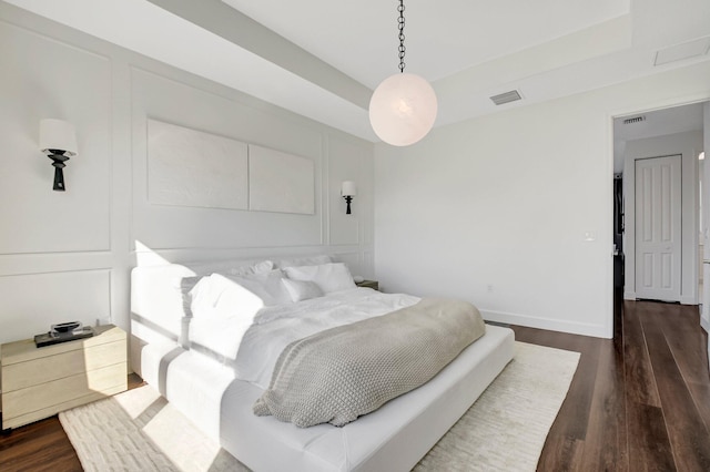 bedroom with a tray ceiling and dark wood-type flooring