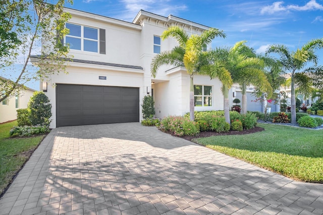 view of front facade with a garage, a front lawn, decorative driveway, and stucco siding