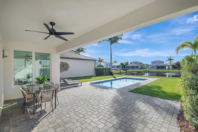 view of swimming pool with a lawn, a patio, ceiling fan, and a water view