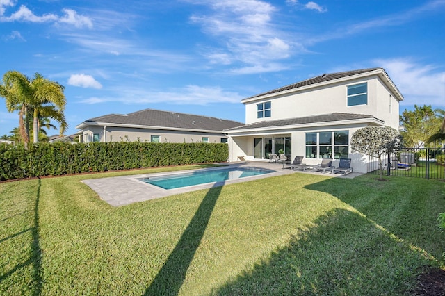 rear view of property with a fenced in pool, a patio, and a yard