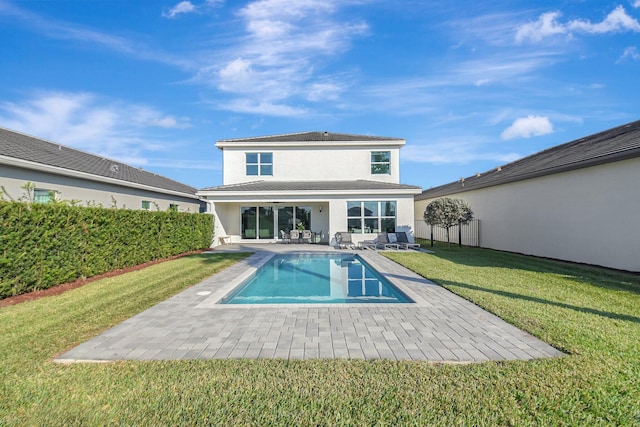 rear view of property featuring a fenced in pool, a patio, and a lawn