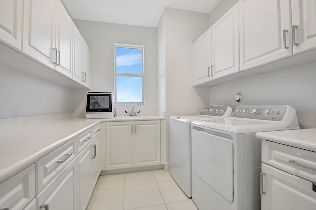 washroom featuring light tile patterned floors, sink, cabinets, and washing machine and clothes dryer