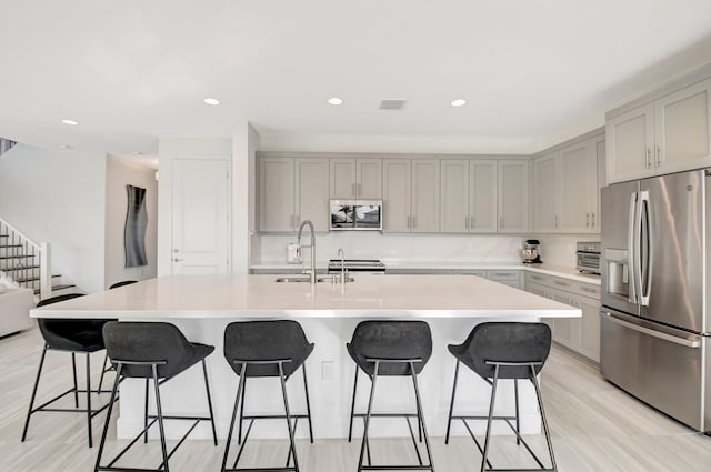 kitchen with sink, a kitchen bar, an island with sink, and appliances with stainless steel finishes