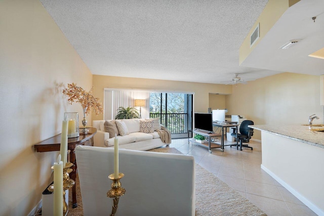 living room with ceiling fan, light tile patterned floors, sink, and a textured ceiling