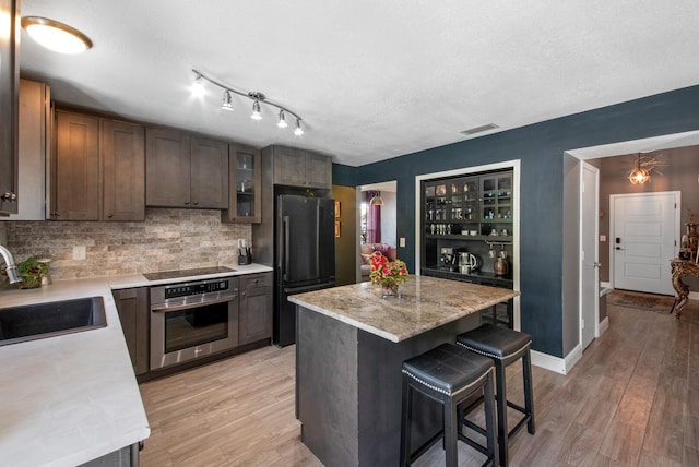 kitchen with sink, a breakfast bar area, a center island, light hardwood / wood-style flooring, and black appliances