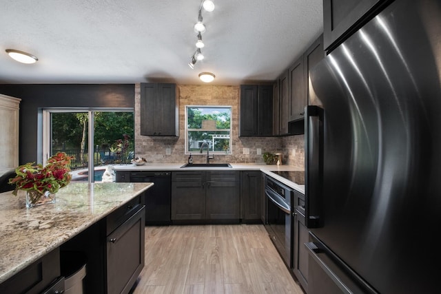 kitchen with sink, decorative backsplash, black appliances, and a textured ceiling