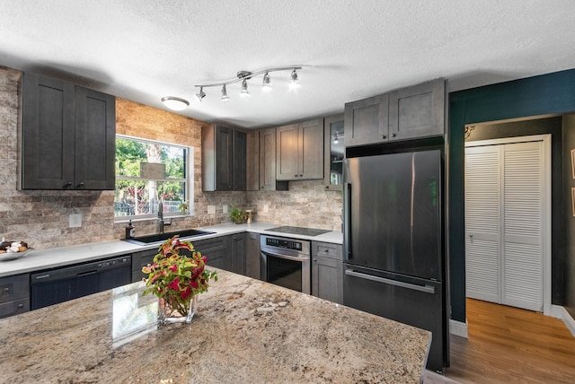 kitchen featuring sink, black appliances, hardwood / wood-style floors, and light stone countertops