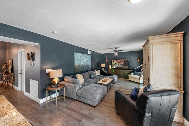 living room featuring hardwood / wood-style flooring, a textured ceiling, and ceiling fan