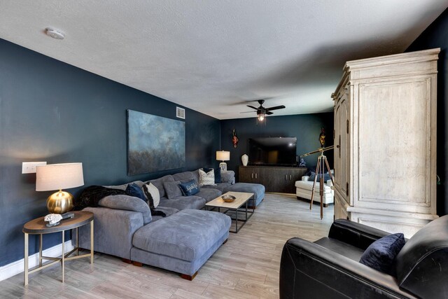 living room featuring ceiling fan, sink, light hardwood / wood-style floors, and a textured ceiling