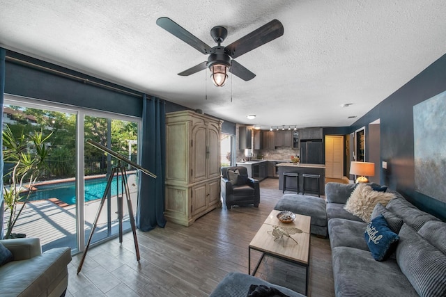 living room featuring a textured ceiling, dark wood-type flooring, and ceiling fan