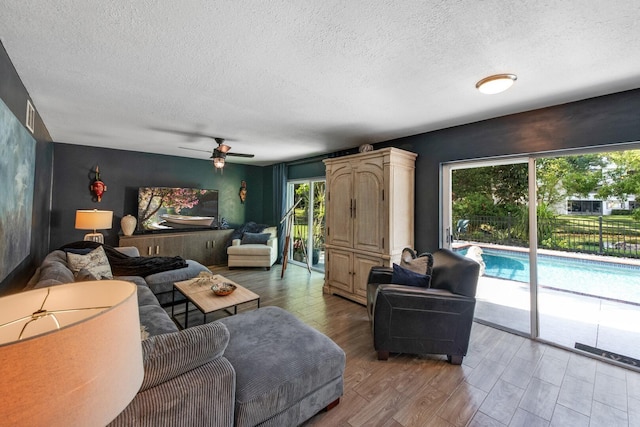 living room with ceiling fan, hardwood / wood-style floors, and a textured ceiling