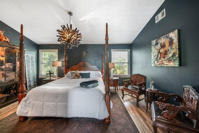 bedroom featuring hardwood / wood-style flooring, lofted ceiling, an inviting chandelier, and multiple windows