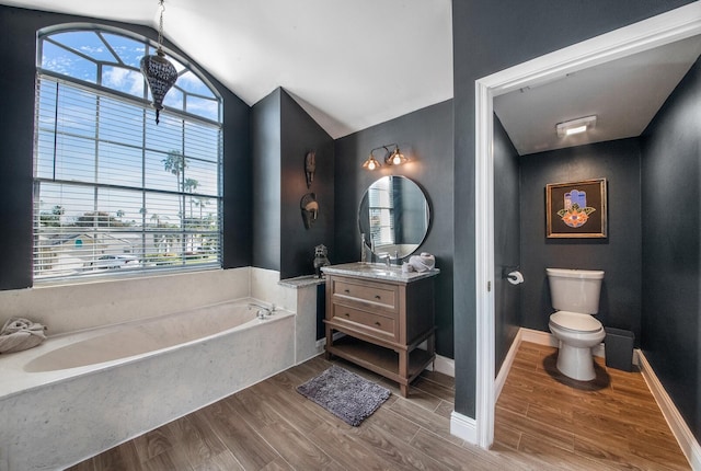 bathroom with lofted ceiling, toilet, vanity, hardwood / wood-style floors, and a washtub