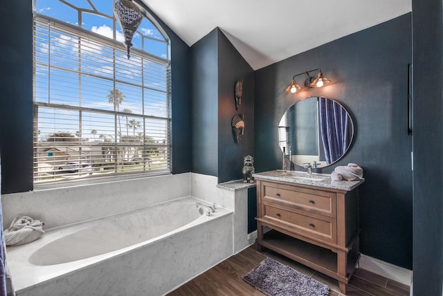 bathroom with hardwood / wood-style floors, a wealth of natural light, a bathing tub, and vaulted ceiling