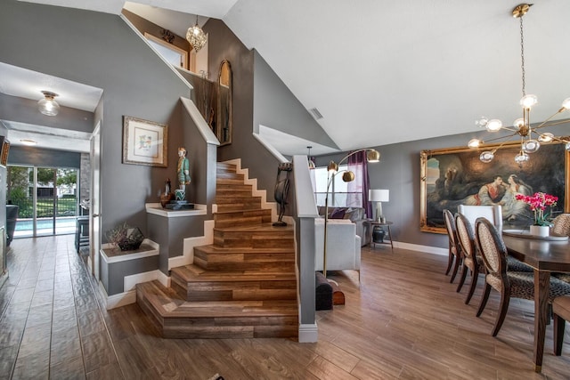 staircase featuring hardwood / wood-style flooring, high vaulted ceiling, and a notable chandelier