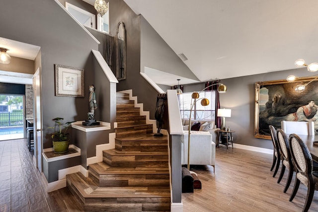 staircase featuring hardwood / wood-style floors and high vaulted ceiling